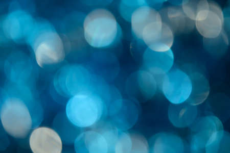 Bokeh photo. Holiday background. Christmas lights. background. Defocused sparkles. New Year backdrop. Festive wallpaper. Blinks. Carnival. Retro style photo. Blue.の写真素材