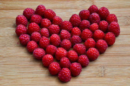 Raspberry heart. Valentines day background. Fresh raspberries from village garden. Love berries...