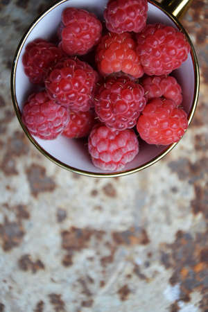 Raspberries in golden cup on grunge vintage background. Organic fresh raspberries in the...