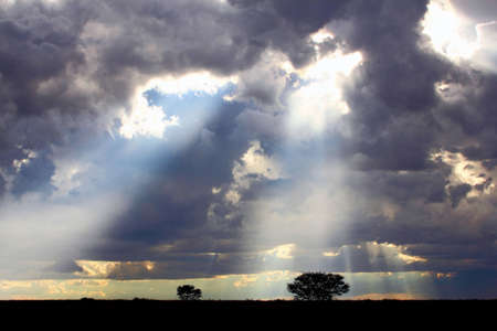 Bright sun rays through dark cloudsの写真素材