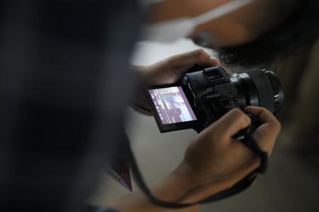 Close up of a man holding a modern photo camera while looking at the screenの写真素材