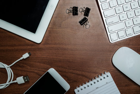 overhead of office table with notebook, computer keyboard and mouse, tablet pc and smartphone. copy spaceの写真素材