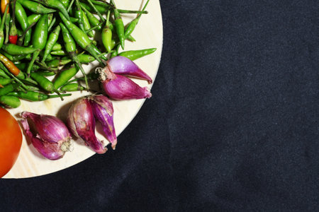 red onion and green chili with a black backgroundの写真素材