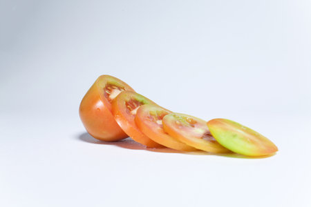 the concept of tomato fruit is cut into pieces with a white backgroundの写真素材