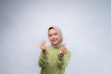 Asian beautiful smiling girl showing love sign with hand at Copy Space Advertising Your Text, isolated white background.の写真素材