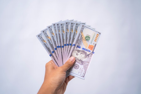 Hand holding a fan of hundred dollar bills. Payment, profit, and business conceptの写真素材
