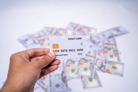 Hand Holding Credit Card Over Dollar Bills