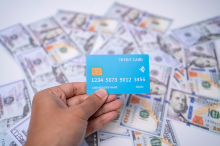 Hand Holding Blue Credit Card Over Dollar Bills