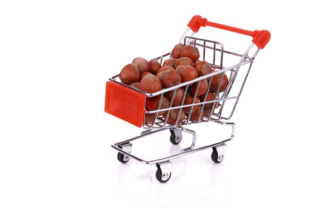Nuts in miniature shopping cart isolated on white backgroundの写真素材