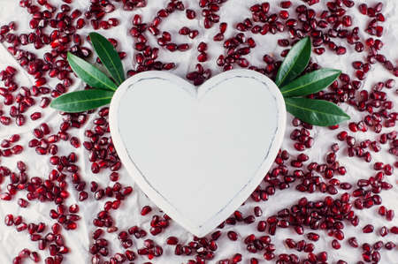 The heart and pomegranate seeds on the white background. Top viewの写真素材