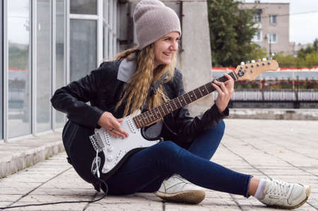 Beauty girl playing on guitar on rock