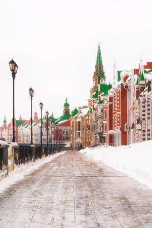 Russia, Yoshkar-Ola, Bruges embankment, March 09, 2019, cloudy winter day, view of the buildings. Parapet by the river on the left, colored brick buildingsのeditorial素材