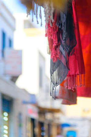 Hanging shawls on a street background, Mahdia, Tunisia, Red and blue shawls hanging from above, on the left a bright sunny street, blurred backgroundの写真素材