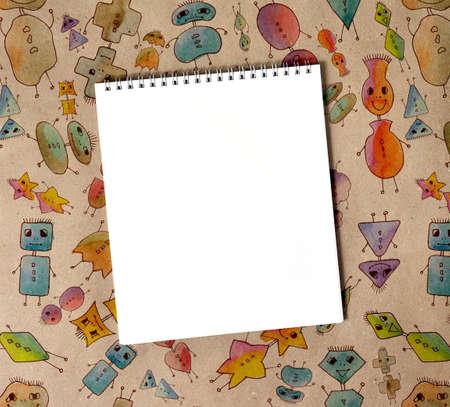 Blank notepad close up on craft paper with robots. Background with cartoon robots drawings for...