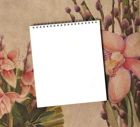 Blank notepad close up on craft paper with flowers. Background with bouquets of orchids for...