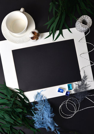 The background is black with a cup on a saucer, eucalyptus leaves, flatlay white frame .Watercolor...