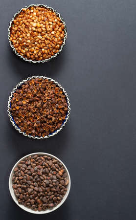 Three round bowls with Siberian pine nuts. Peeled nut kernels, their shells, whole cone grains. Top...