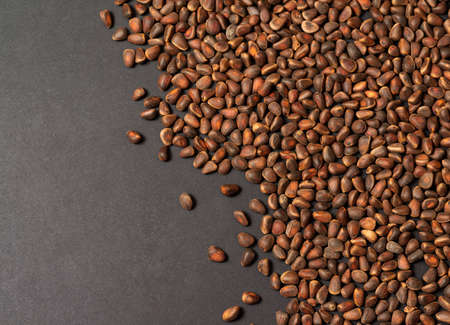 Scattered pine nuts on a black background, top view. On the left there is an empty space for text, background for recipes, articles.の写真素材
