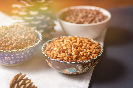 Still life from bowls with peeled pine Siberian nuts, shell skins and whole nuts. On a layer with a...