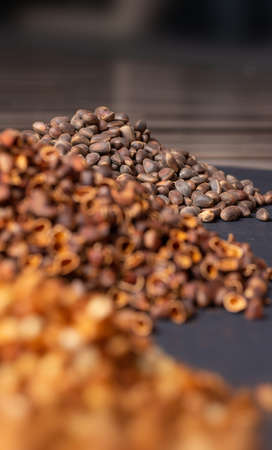 A slide of pine nuts, in the foreground, blurred heaps of peeled nuts and their shells. Vertical...