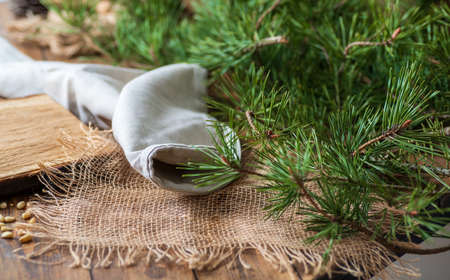 Background of pine branches with green needles, rough gray linen fabric, burlap, on a wooden table....