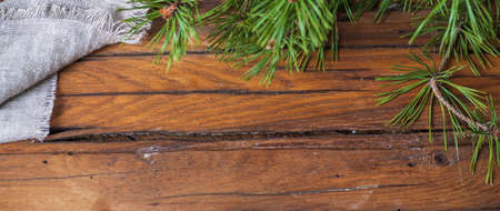 Wooden table with pine branches with green long needles, a fragment of rough gray fabric. Top view, background with diet food, blank space for a recipe. Narrow panorama.の写真素材