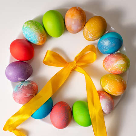 Colored eggs for Easter on a white background spread out in a circle surrounded by colored ribbons. Spiral ribbonsの写真素材