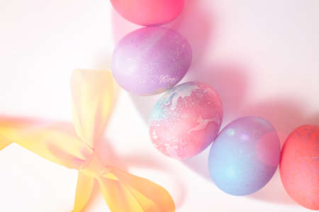 Colored eggs for Easter on a white background are laid out in a circle surrounded by a ribbon...