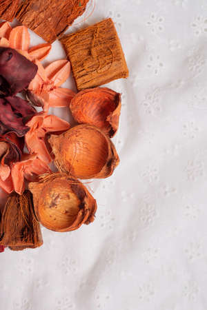 On the left side dried flowers and petals of buds on a white fabric close-up. Aromatherapy for the house on a hot summer day. Empty space for text, inscriptions. Vertical.の写真素材
