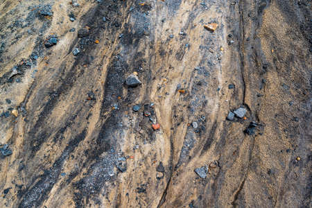 The texture is a close-up of the surface of the earth of sand and stones, blurred by a stream....