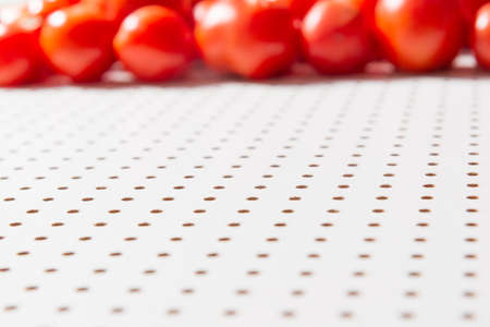 White table in a hole, in the distance blurred rows of red tomatoes. Background with empty space for inscriptions about fresh vegetables and healthy food.の写真素材