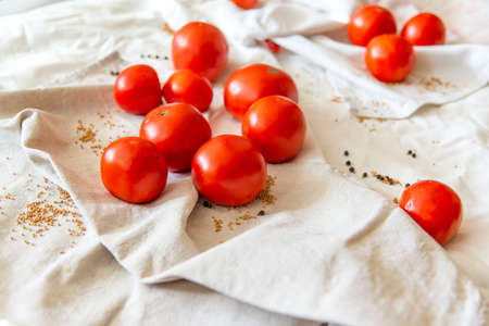 Red tomatoes on a linen towel. In the folds of the fabric of the moaning pepper and mustard in the grains. Ripe vegetables for dietary menus, recipes for healthy and healthy food.の写真素材
