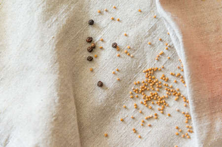 Linen fabric with a pronounced texture and folds. On the surface scattered black pepper and mustard. Empty light background for recipes, menu about healthy country food.の写真素材
