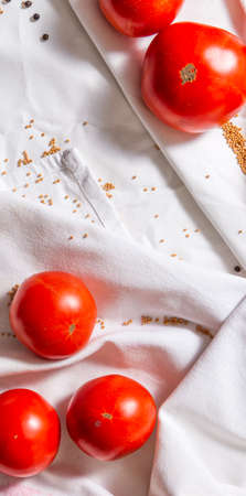 Narrow vertical background with red tomatoes, mustard and pepper. Light fabric with folds, top view. Empty space for a text about healthy food and the benefits of vegetables.の写真素材