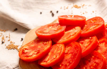 Tomato slices on the board close-up. The distant background is blurred. Spices are scattered. Empty space for menus, recipes and texts.の写真素材