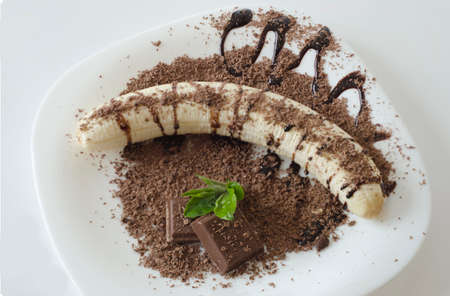 Banana in chocolate and ornamental leaves isolated on white backgroundの写真素材