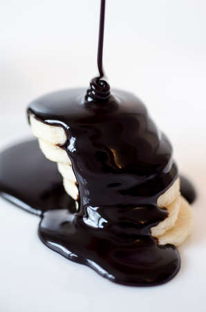 Slices of banana with poured chocolate isolated on white backgroundの写真素材
