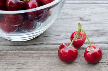 Cherries on wood and in bowl isolated on wood background
