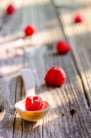 Rasberry in wooden spoon isolated on vintage wooden backgroundの写真素材
