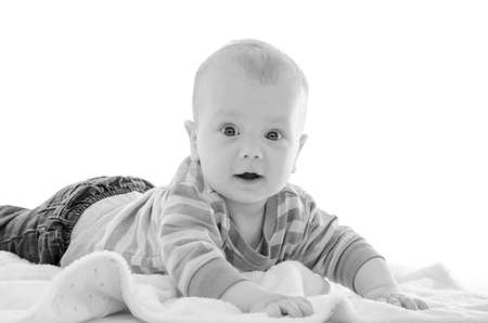 Infant baby boy smiling on a white blanket isolated on white