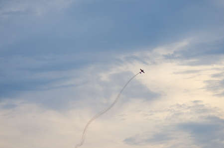 Acrobatic plane aircraft with smoke behind on blue skyの写真素材