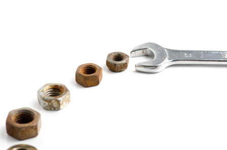 Steel wrench key and many rusted nuts isolated on white backgroundの写真素材