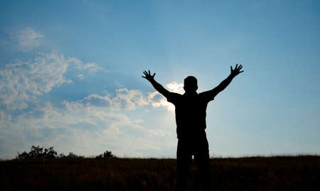 Silhouette of man worship with hands raised to the sky in nature concept of religion, prayer, worshipの写真素材