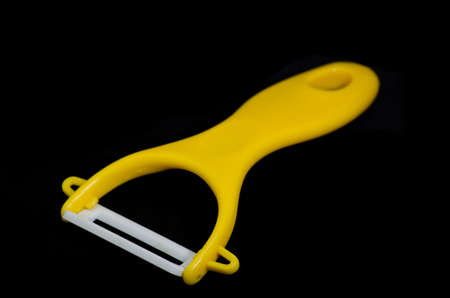 Yellow ceramic peeler for fruits and vegetables isolated on blackの写真素材