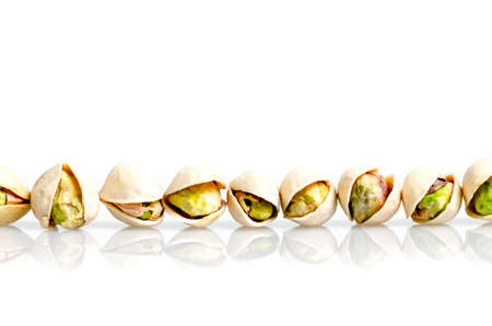 Roasted and salted pistachio with shell in line and reflexion isolated on white background. Conceptual photoの写真素材