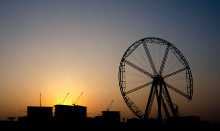 Silhouette on industrial zone with crane and huge wheel under construction at sunset in Dubaiの写真素材