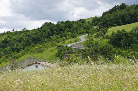 Landscape areas, roof house and winding road into the hills - Cloudy day in summer season -...