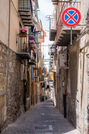 A narrow street in Cefalu, Sicily - Italy. Washing and awnings hang from the balconies of buildingsの写真素材