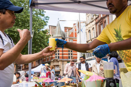 African ethnic preparing pina colada in pineapple on street - Food Street Market Reading, United...