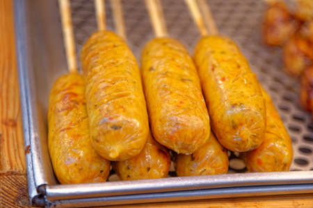 Thai food. Grilled sausages on sticks on food street market - Bangkok, Thailand